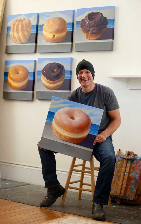 Jay Mercado shows off some of his “Ocean Beach Donuts” paintings. The subjects are posed on a seawall near his Richmond District home. Photo: Liz Hafalia / The Chronicle / ONLINE_YES